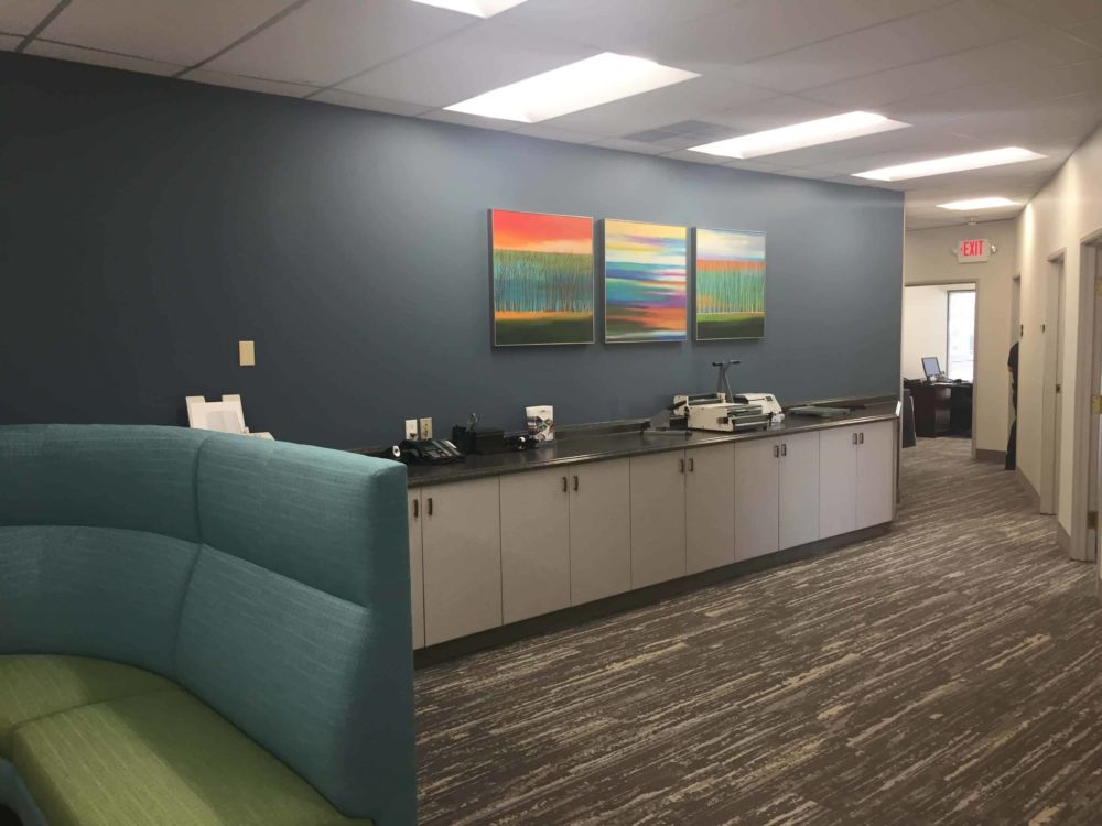 Image of three bright artwork canvases over corporate work area